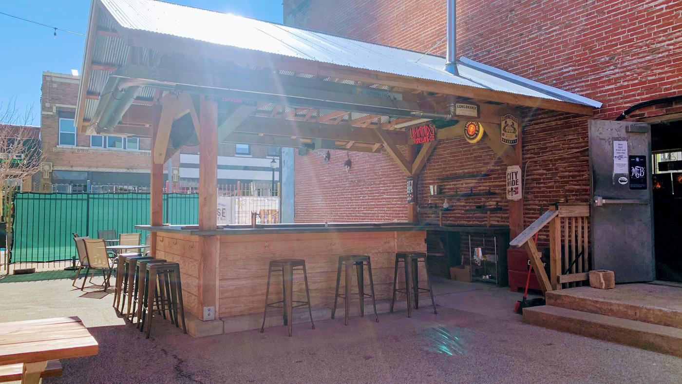 The covered outdoor bar on the back patio, timber built against a brick wall